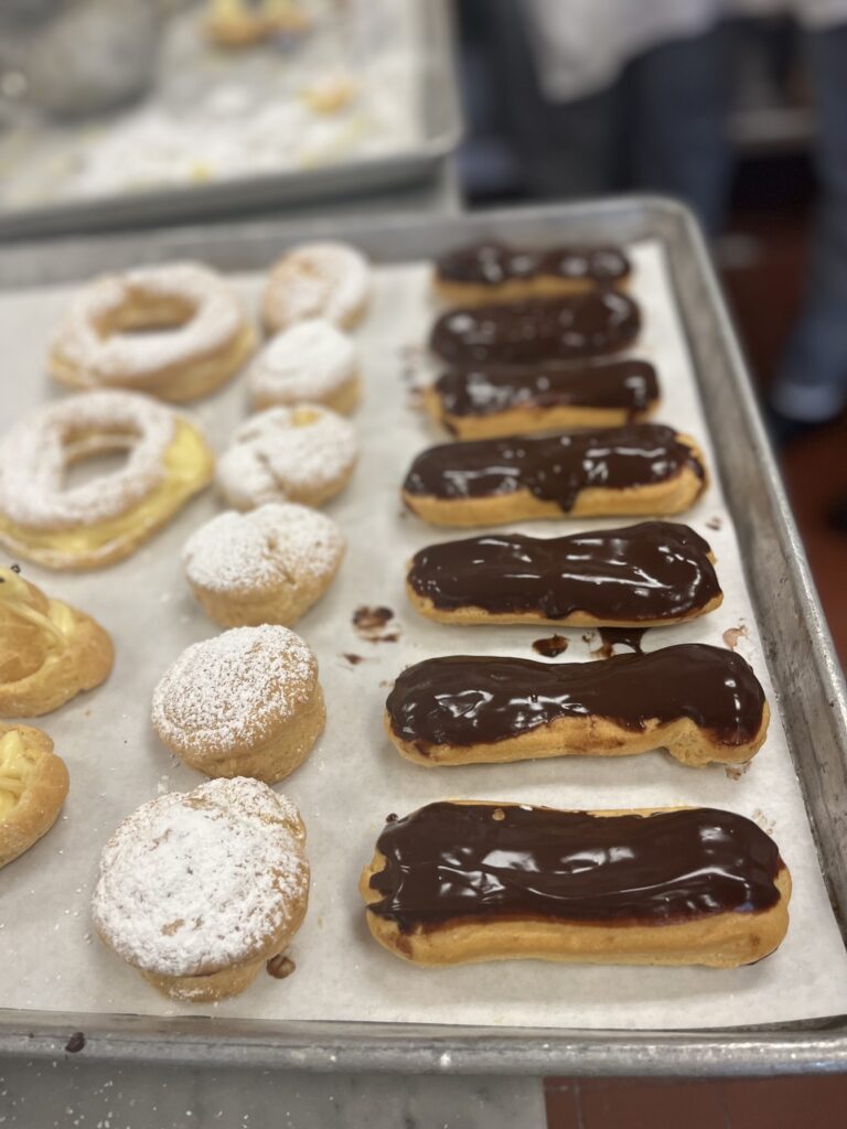 Tray with Pâte à Choux presentation with Eclairs, sugar powdered Profiteroles and others.