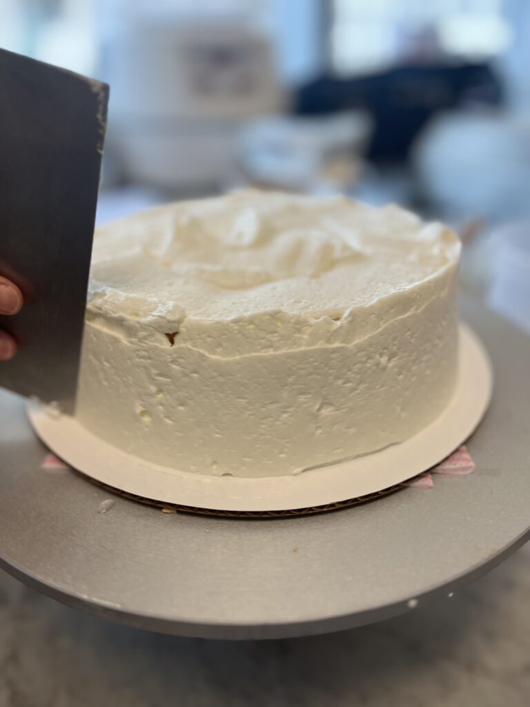 Smoothing the side of the cake with our scraper using the turntable.